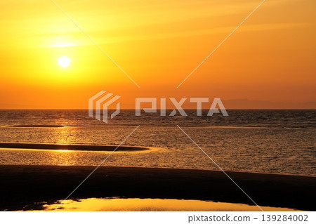 The sunset over the tidal flats, bathed in golden light, and the shimmering surface of the water create a beautiful scene. The sunset over the tidal flats, bathed in golden light, and the shimmering surface of the water create a beautiful scene. 139284002