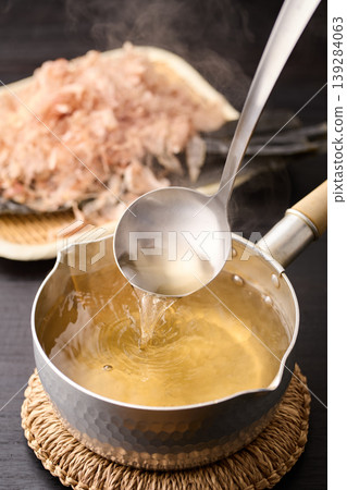 Scoop up the piping hot broth with a ladle. Scoop up the piping hot broth with a ladle. 139284063