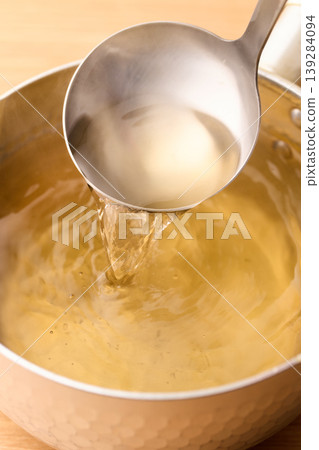 用湯匙舀起滾燙的高湯。 用湯匙舀起滾燙的高湯。 139284094