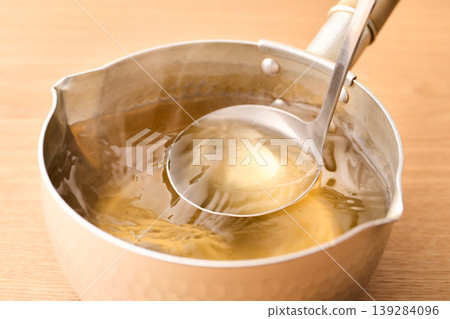 用湯匙舀起滾燙的高湯。 用湯匙舀起滾燙的高湯。 139284096