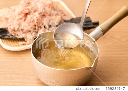 Scoop up the piping hot broth with a ladle. Scoop up the piping hot broth with a ladle. 139284147