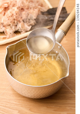 Scoop up the piping hot broth with a ladle. Scoop up the piping hot broth with a ladle. 139284148
