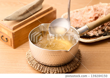 Scoop up the piping hot broth with a ladle. Scoop up the piping hot broth with a ladle. 139284150