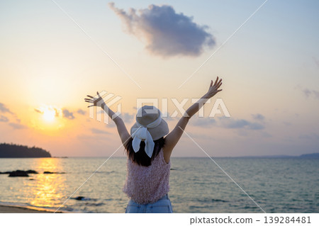 The back view of a Japanese woman who is happy watching the sunset over the sea. The back view of a Japanese woman who is happy watching the sunset over the sea. 139284481