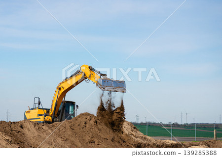 Excavator loading soil on construction site under clear sky 139285388