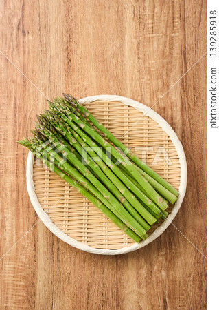 新鮮的綠色蘆筍,春季時令蔬菜,擺放在竹篩上。 新鮮的綠色蘆筍,春季時令蔬菜,擺放在竹篩上。 139285918