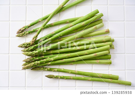 Fresh green asparagus, spring seasonal vegetables arranged on white tiles. Fresh green asparagus, spring seasonal vegetables arranged on white tiles. 139285938