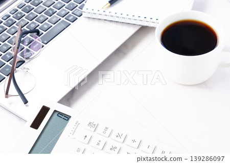 Image of a man working at his desk with a laptop and a calculator while drinking freshly brewed coffee 139286097