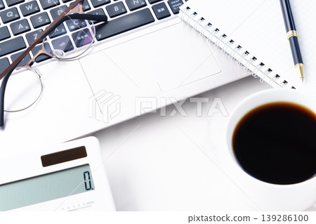 圖片中,一位男士在辦公桌前工作,一邊喝著剛煮好的咖啡,一邊使用筆記型電腦和計算器 圖片中,一位男士在辦公桌前工作,一邊喝著剛煮好的咖啡,一邊使用筆記型電腦和計算器 139286100