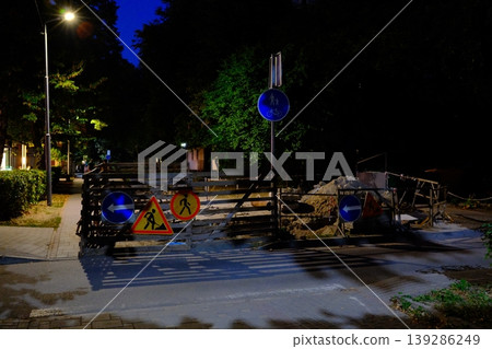 A road is blocked off with construction signs and wooden barriers at night A road is blocked off with construction signs and wooden barriers at night 139286249