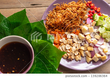 Traditional Thai miang kham ingredients with betel leaves lime chili peanuts coconut and sweet sauce ready to wrap fresh herbs balanced sweet sour salty flavors 139286364