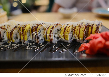Sushi with mango, cheese, and dark sauce sits on a plate with pickled ginger Sushi with mango, cheese, and dark sauce sits on a plate with pickled ginger 139286383