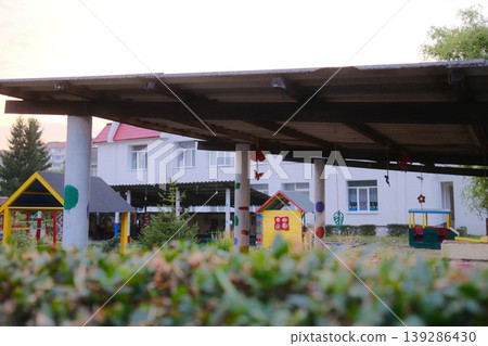 Outdoor playground for children with colorful playhouses and bushes in the foreground Outdoor playground for children with colorful playhouses and bushes in the foreground 139286430