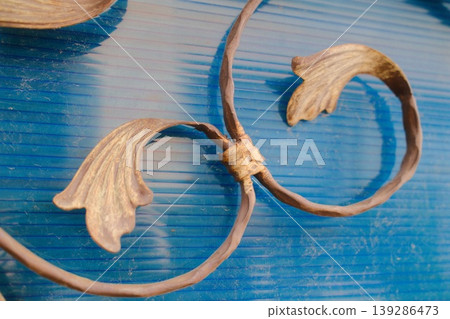 Ornate metalwork features leaf shapes and swirling lines against a textured blue surface 139286473