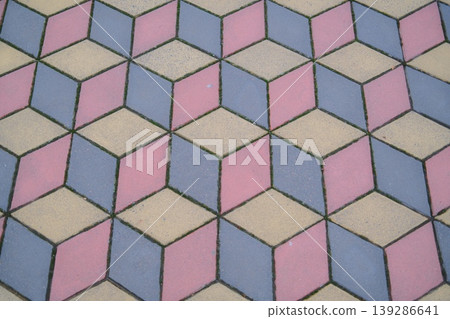Colored concrete pavers are arranged in a cube pattern forming a walkway surface Colored concrete pavers are arranged in a cube pattern forming a walkway surface 139286641