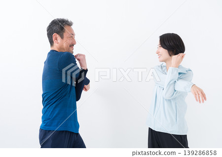 一對中年夫婦身穿運動服，正在做伸展運動。 139286858