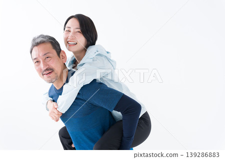 一對中年夫婦穿著運動服,背著嬰兒。 一對中年夫婦穿著運動服,背著嬰兒。 139286883