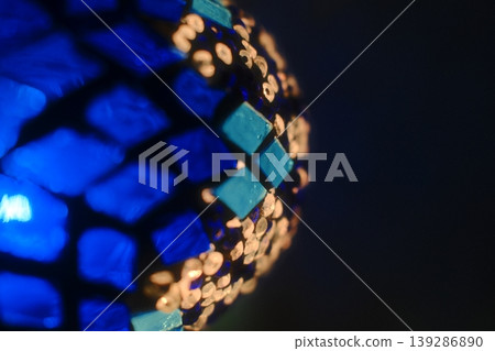 A spherical mosaic with blue tiles and light pieces is illuminated in the dark 139286890