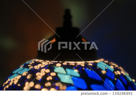 A glowing Turkish lamp features blue and white mosaics. The lamp is lit in dim light 139286891