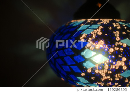 Light shines through a blue, mosaic-tiled turkish lamp, creating a warm glow 139286893