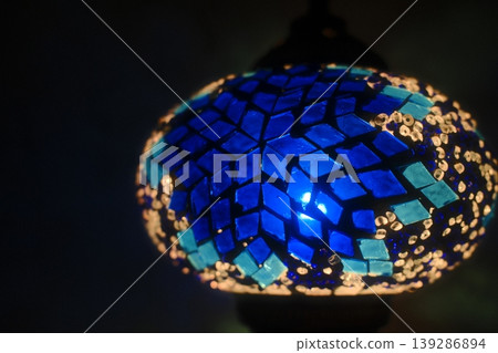 A glass mosaic lamp with light shining through the blue and aqua tiles 139286894