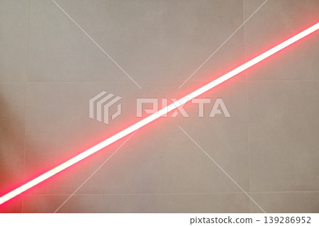 A bright, red neon strip emits light at an angle on a neutral wall A bright, red neon strip emits light at an angle on a neutral wall 139286952