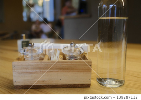 Water bottle, salt and pepper, and napkins rest on a wooden table Water bottle, salt and pepper, and napkins rest on a wooden table 139287112