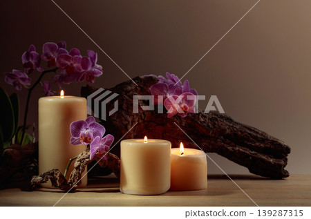 Orchid flowers and burning candles on a background of old wooden snags. 139287315