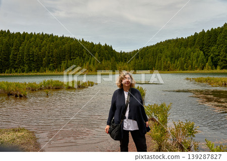 Mature woman posing peacefully by Lagoa dos Canarios in the Azores, Portugal Mature woman posing peacefully by Lagoa dos Canarios in the Azores, Portugal 139287827