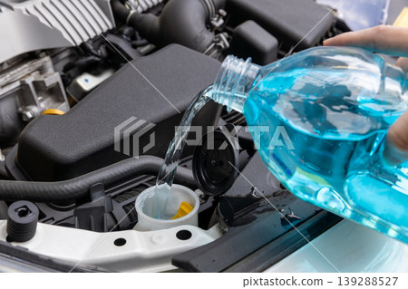 I'm opening the hood of my car and refilling the windshield washer fluid. I'm opening the hood of my car and refilling the windshield washer fluid. 139288527
