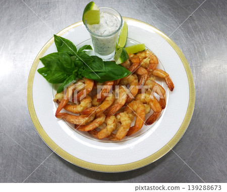 shrimp with sauce and lime wedges on a round white plate shrimp with sauce and lime wedges on a round white plate 139288673