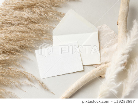 Card and envelope mockup on beige stone with driftwood and pampas grass, wedding stationery Card and envelope mockup on beige stone with driftwood and pampas grass, wedding stationery 139288697