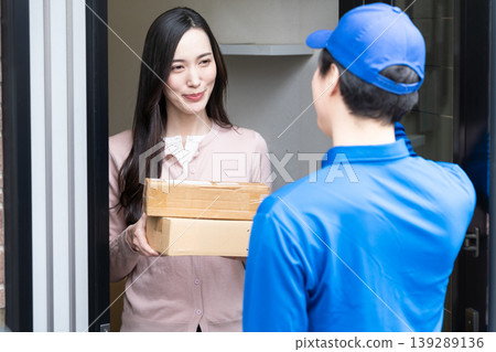 一位年輕女子從快遞員手中接過包裹:生活寫照。 一位年輕女子從快遞員手中接過包裹:生活寫照。 139289136