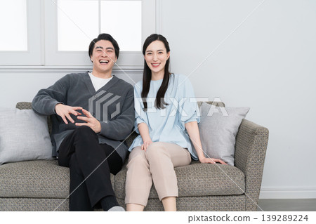 A young man and woman relaxing on a sofa: Lifestyle image 139289224