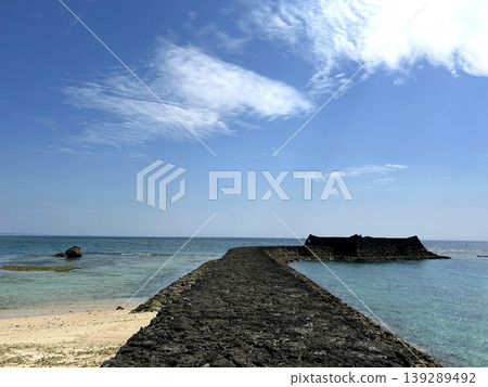 The Okinawan sea stretches out into the ocean, with stone breakwaters extending into the sea and white sand beaches. The Okinawan sea stretches out into the ocean, with stone breakwaters extending into the sea and white sand beaches. 139289492
