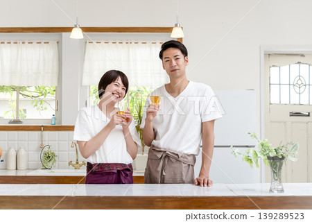 A young couple toasts in the kitchen, both smiling. 139289523