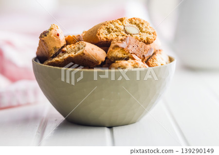 Grissini. Almond Biscotti in Bowl and Scattered Cookies on White Table for Breakfast Snack Grissini. Almond Biscotti in Bowl and Scattered Cookies on White Table for Breakfast Snack 139290149