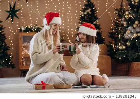 Delicious tea in cups. Mother and daughter are celebrating New Year at home in domestic room Delicious tea in cups. Mother and daughter are celebrating New Year at home in domestic room 139291045