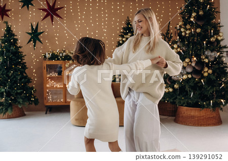Holding the hands. Mother and daughter are celebrating New Year at home in domestic room Holding the hands. Mother and daughter are celebrating New Year at home in domestic room 139291052