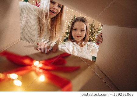 Taking the gift. View from the inside of box. Mother and daughter are looking at the New Year presents Taking the gift. View from the inside of box. Mother and daughter are looking at the New Year presents 139291062