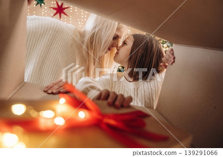 Bright garlands. View from the inside of box. Mother and daughter are looking at the New Year presents 139291066