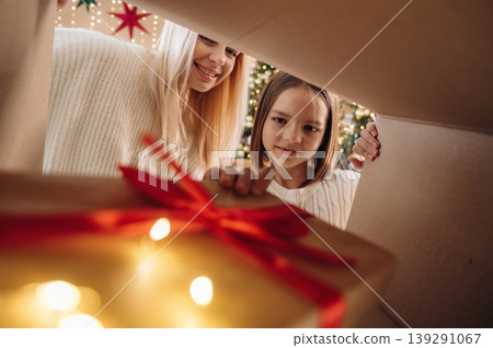 Bright garlands. View from the inside of box. Mother and daughter are looking at the New Year presents Bright garlands. View from the inside of box. Mother and daughter are looking at the New Year presents 139291067