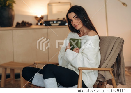 Relaxed woman is sitting in the chair and reading the book at home Relaxed woman is sitting in the chair and reading the book at home 139291141