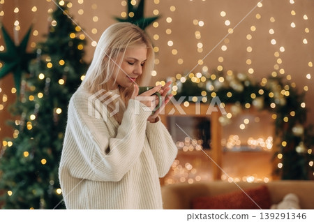 Beautiful woman is standing in the room with New Year garlands and fir Beautiful woman is standing in the room with New Year garlands and fir 139291346