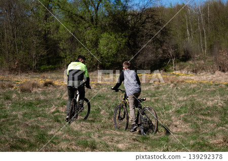 Father and son enjoy a scenic bike ride through a tranquil wooded area. Father and son enjoy a scenic bike ride through a tranquil wooded area. 139292378