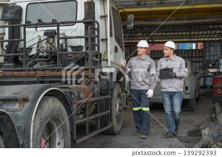 Caucasian and Middle Eastern mid-adult male technicians walk through an Asian container yard while holding a clipboard Caucasian and Middle Eastern mid-adult male technicians walk through an Asian container yard while holding a clipboard 139292393