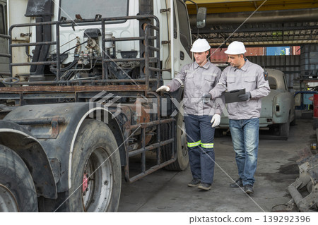 Caucasian and Middle Eastern mid-adult male technicians walk through an Asian container yard while holding a clipboard Caucasian and Middle Eastern mid-adult male technicians walk through an Asian container yard while holding a clipboard 139292396