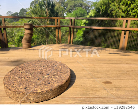 A cork coaster sits on a wooden outdoor table with a blurred forest background in Porto park. Concepts of minimalism, eco-friendly materials, and calm outdoor living A cork coaster sits on a wooden outdoor table with a blurred forest background in Porto park. Concepts of minimalism, eco-friendly materials, and calm outdoor living 139292546