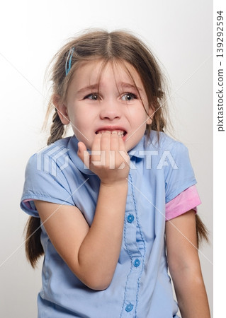 Young girl nervously biting her nails, showing anxiety or worry. 139292594