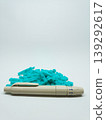 Front view of a lancing device pen and a pile of turquoise sterile blood lancets isolated on a white background 139292617